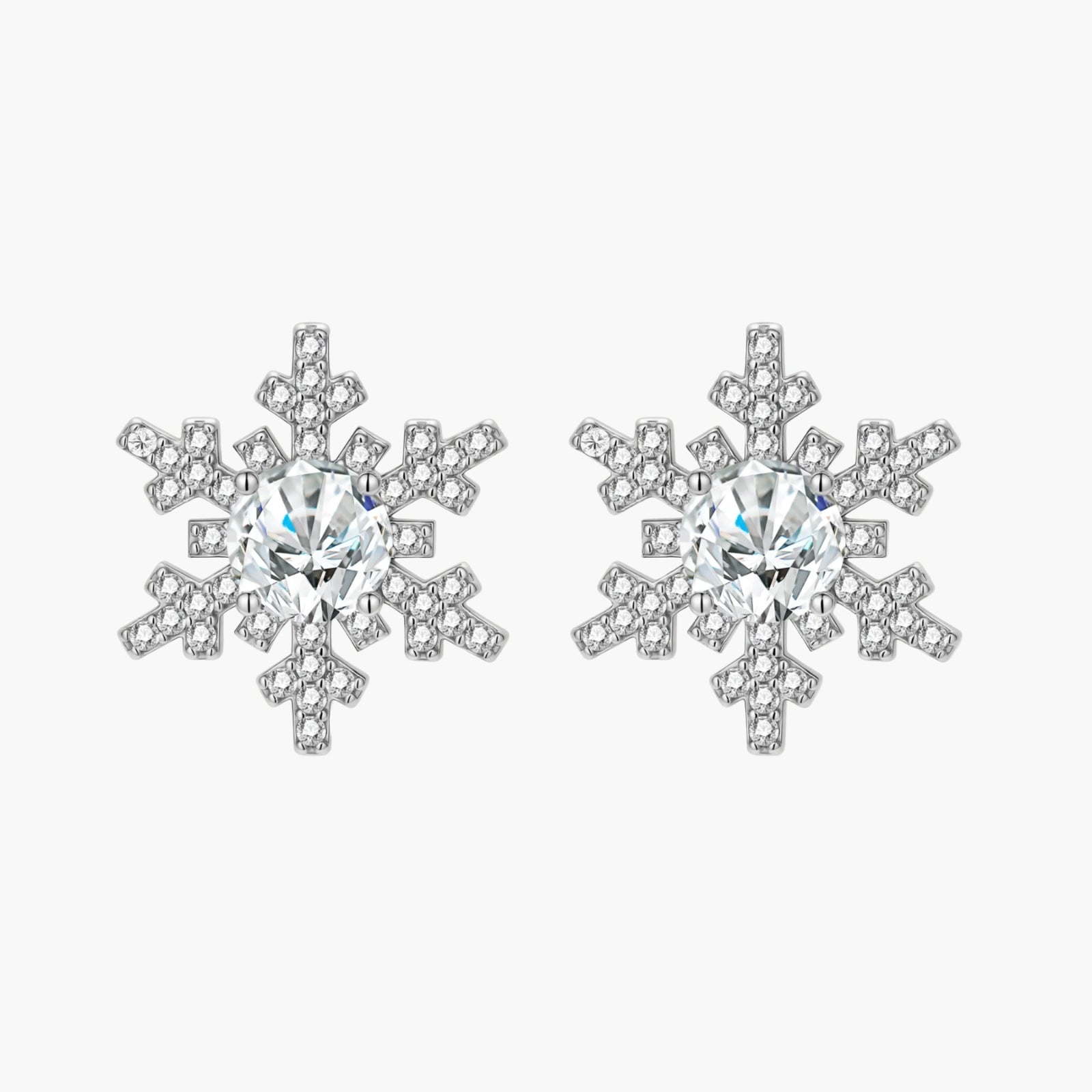 Sterling silver snowflake stud earrings with brilliant moissanite centers and intricate geometric patterns on cream background