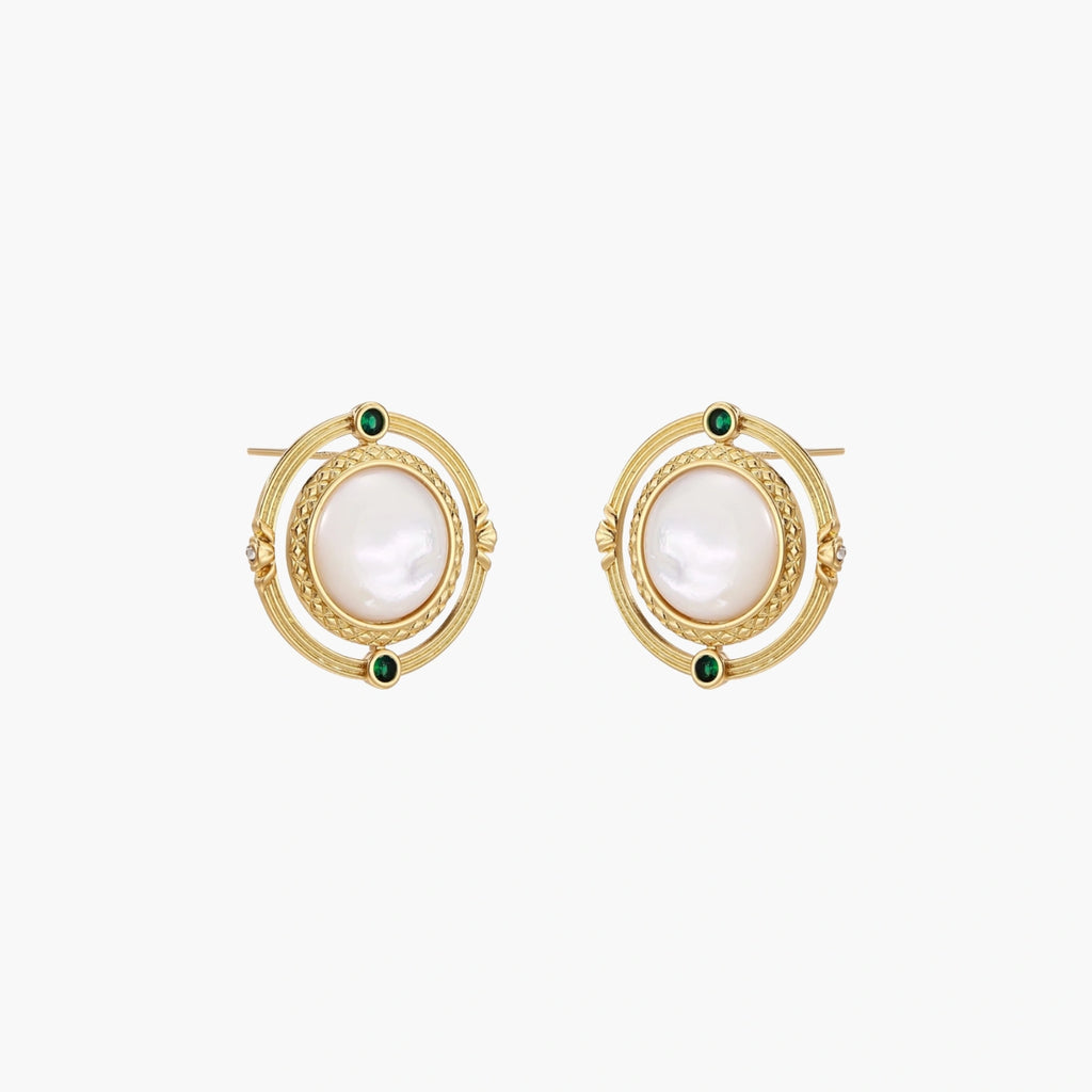 Circular gold stud earrings with iridescent mother-of-pearl center and green zirconia accents on cream background.